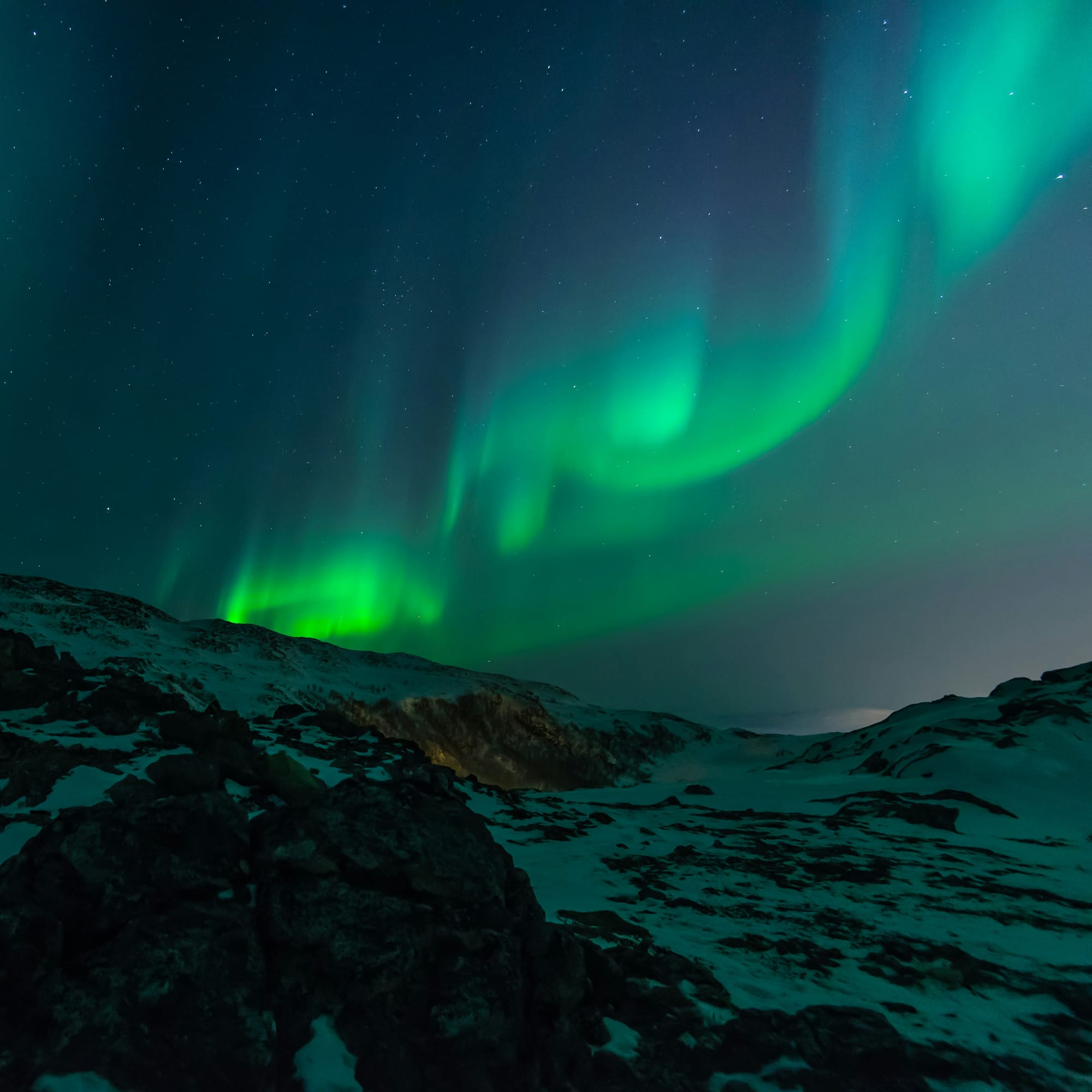 Aurora Borealis (Northern Lights) in Norway with snowy terrain below.